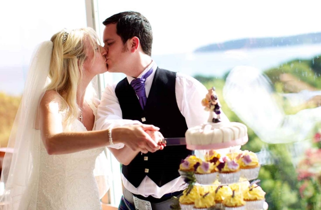 married couple kissing in front of their wedding cake